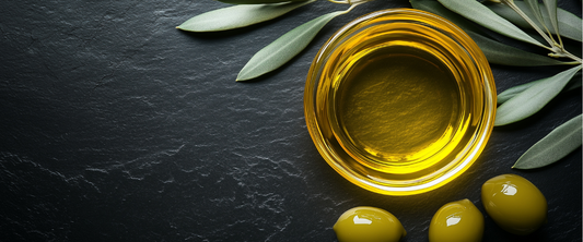 Squalan in einer Schüssel aus Olivenöl mit Oliven und Olivenblättern auf schwarzem Hintergrund.