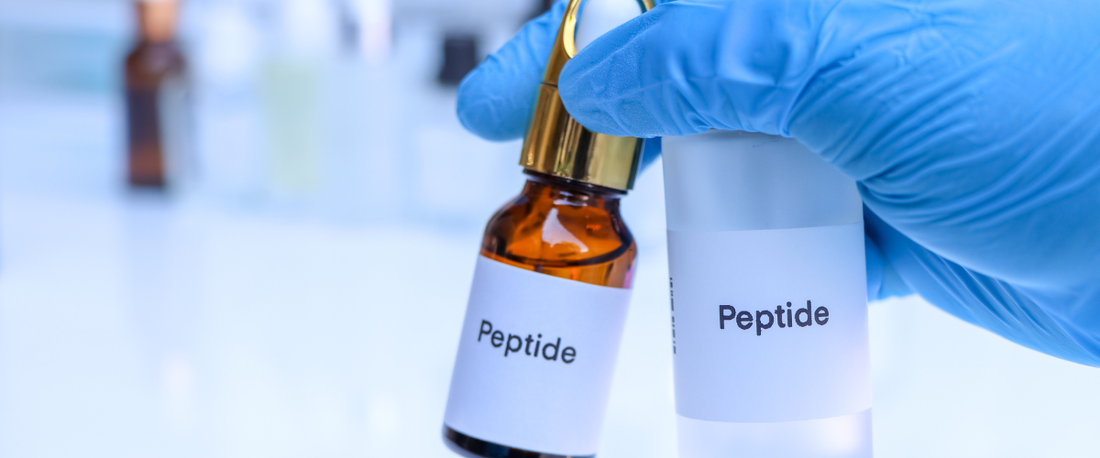 Hand hält zwei Fläschchen mit dem Label Peptide in einem Labor.