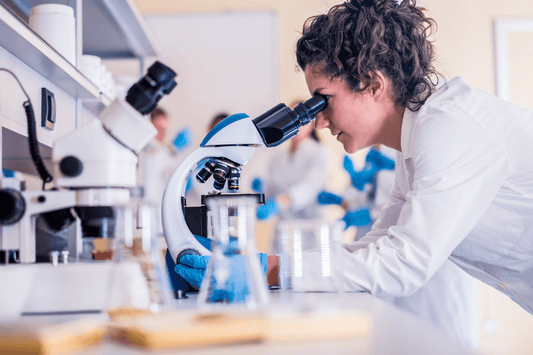 Die Vision einer Wissenschaftlerin, die am Mikroskop in einem modernen Labor arbeitet.