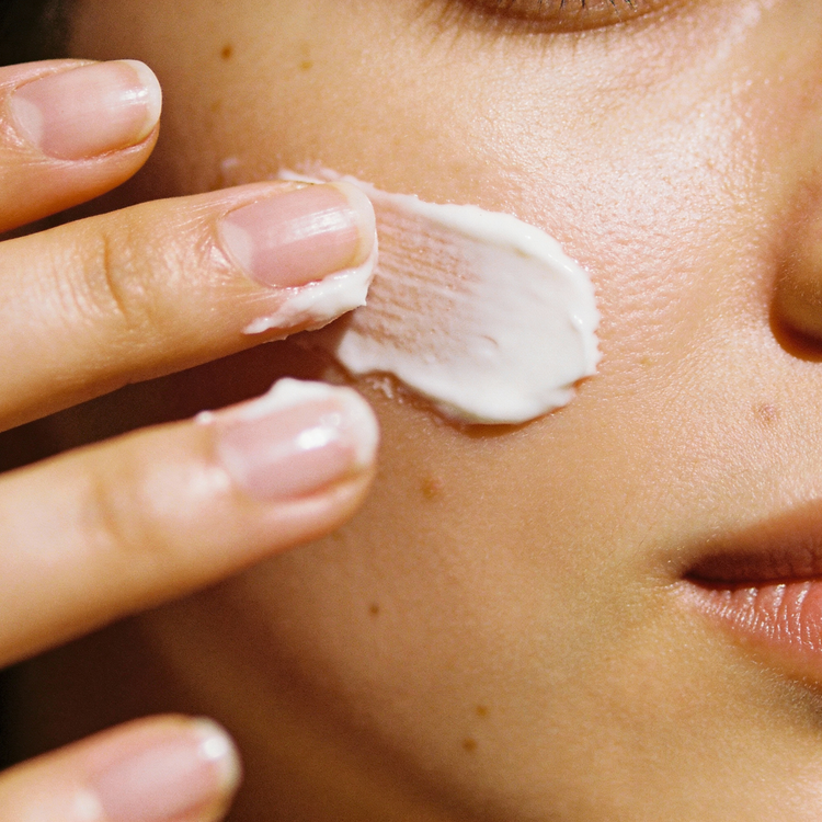 Eine Person trägt Creme auf ihr Gesicht auf, Teil der Collection Cremes.