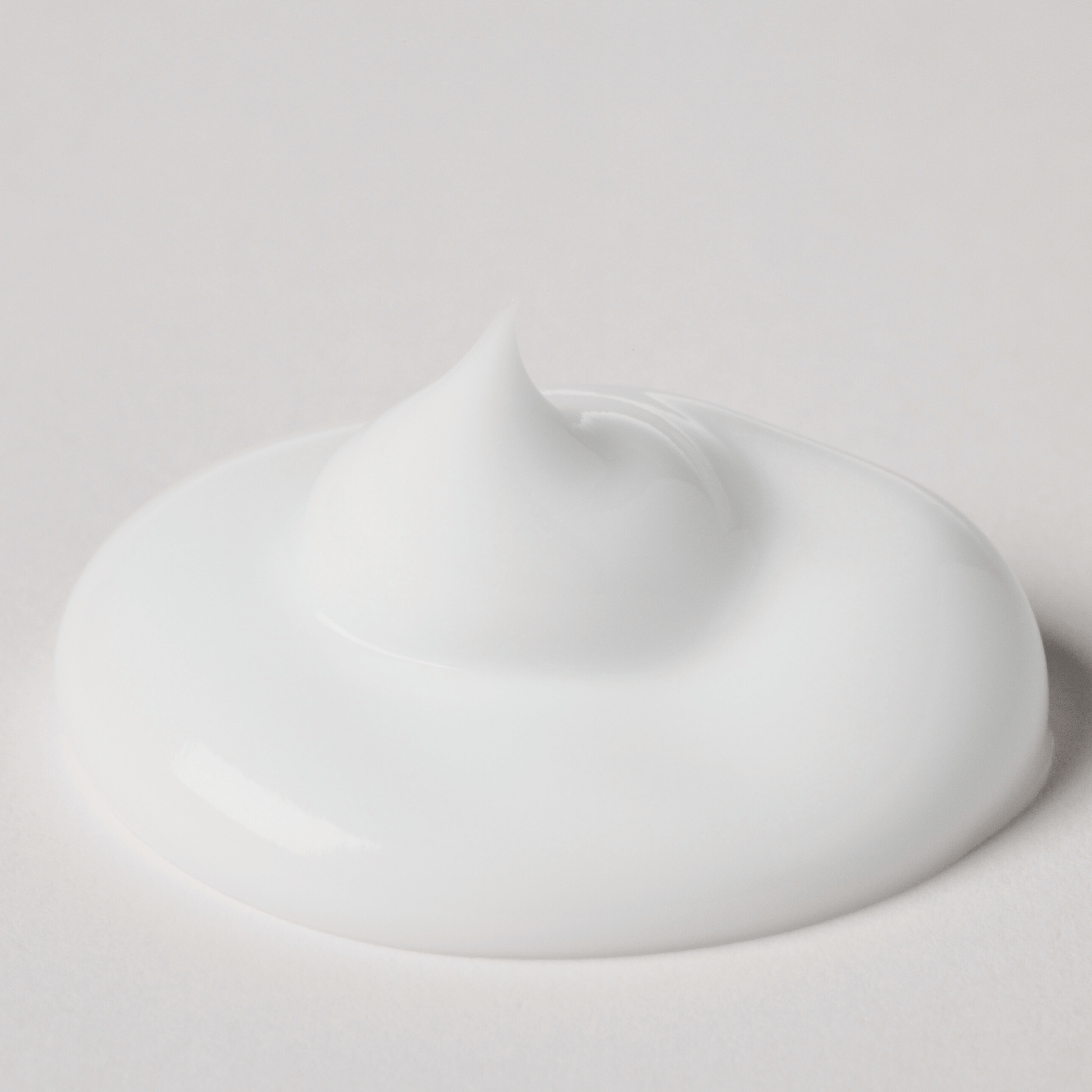 Feuchtigkeitscreme - Hydrating Luminizer in weißer, cremiger Konsistenz auf einem neutralen Hintergrund.