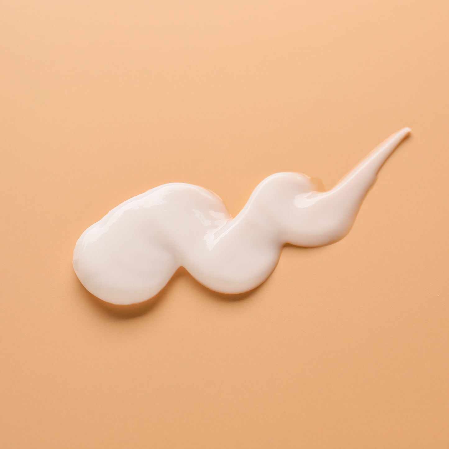 Abschwellende Augencreme in cremiger Textur auf orangefarbenem Untergrund.
